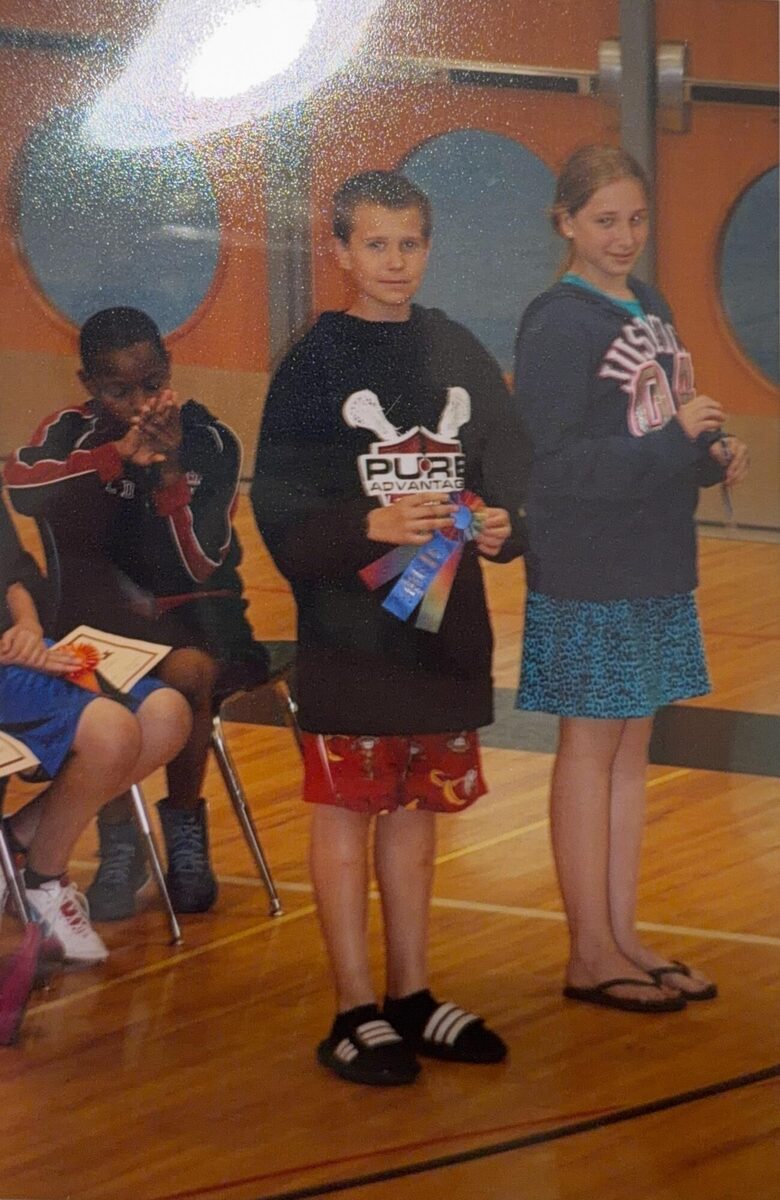 Justin holding a prize ribbon at a school awards event