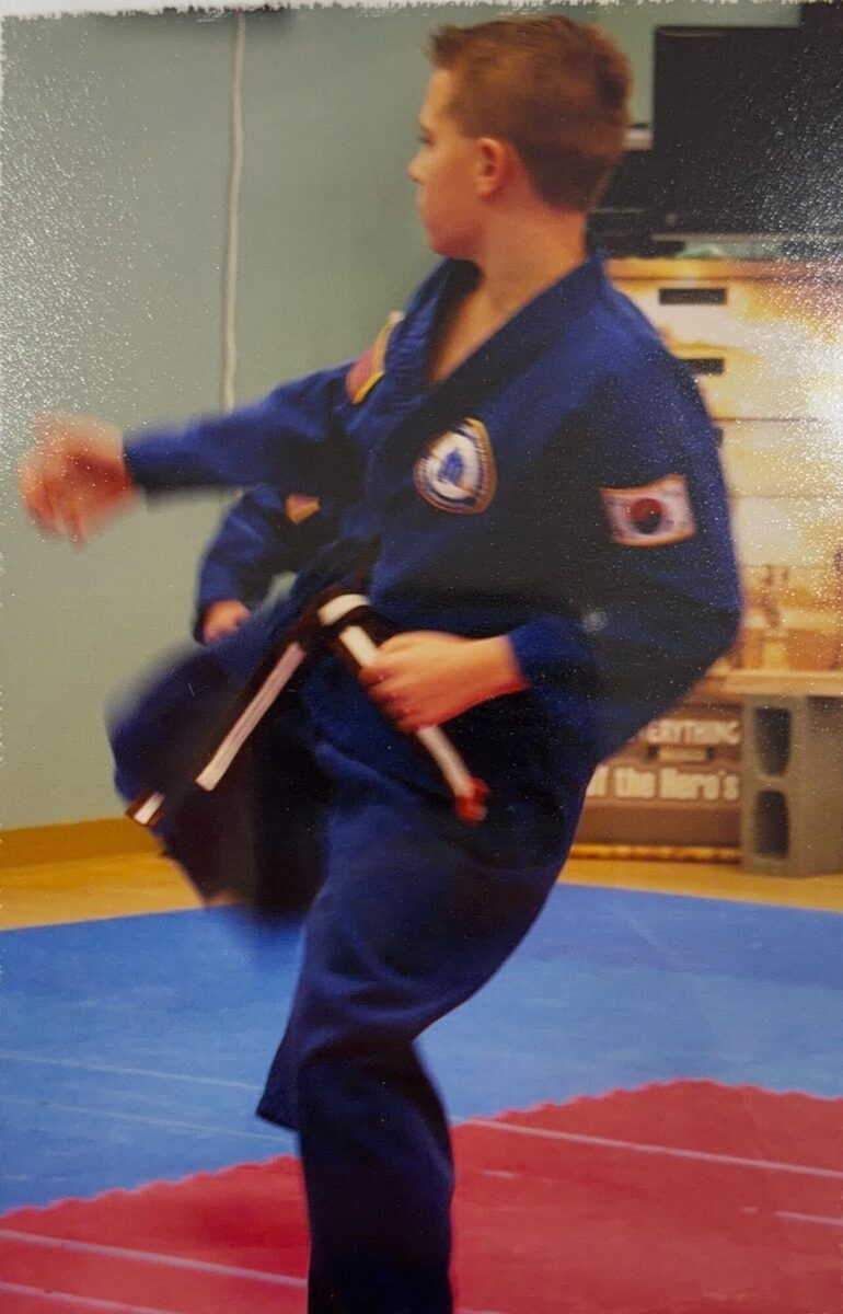 Justin in a blue karate gi throwing a kick